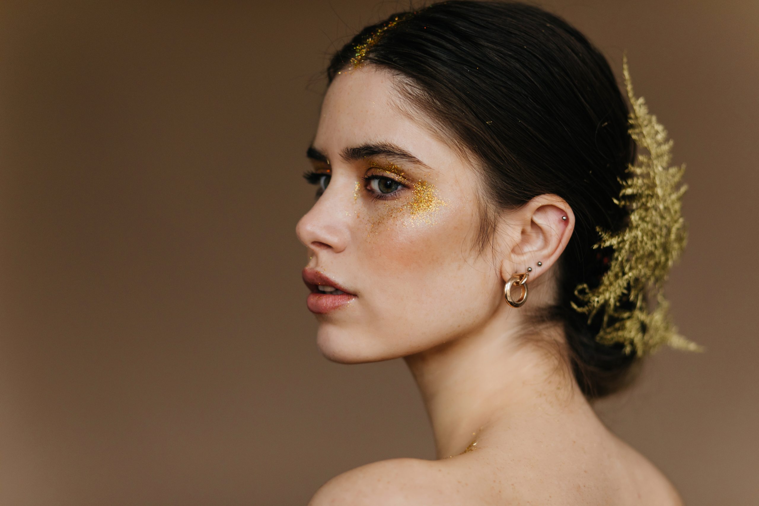 close up portrait of charming woman wears golden earrings. studi